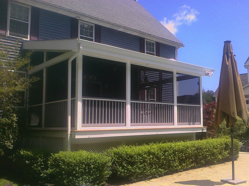 This is an example of a large transitional screened-in back porch design in Boston with decking and a roof extension.