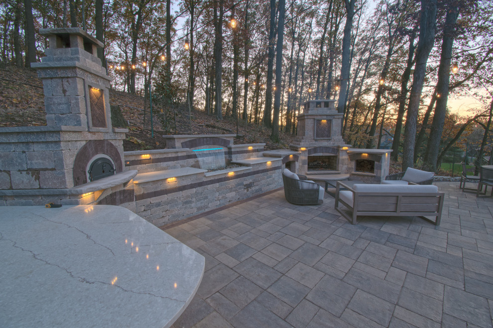 This is an example of a medium sized contemporary back veranda in Other with a fireplace and brick paving.