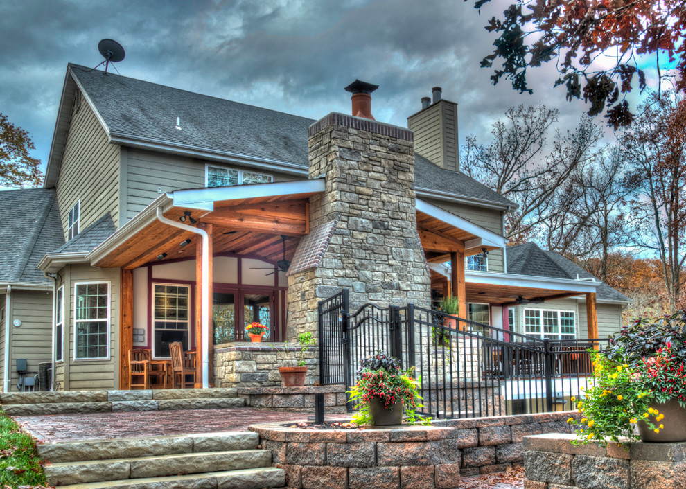 Cette photo montre un grand porche d'entrée de maison arrière montagne avec un foyer extérieur, des pavés en pierre naturelle et une extension de toiture.