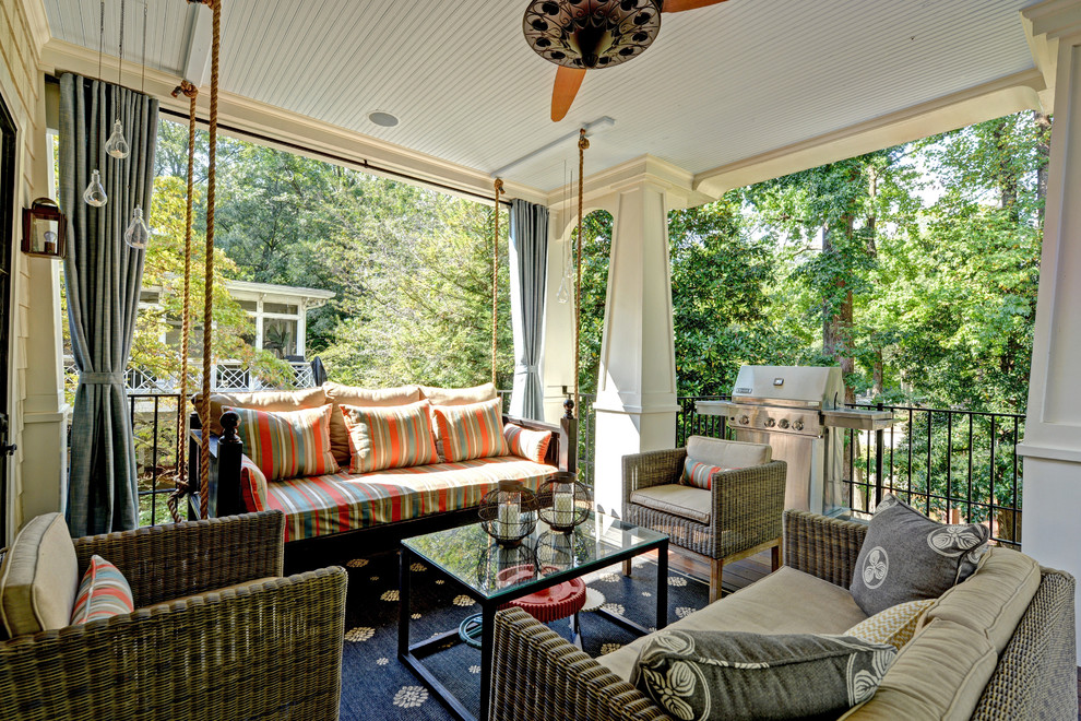 Exemple d'un grand porche d'entrée de maison arrière chic avec une extension de toiture et une terrasse en bois.