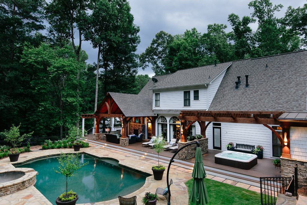 Réalisation d'un très grand porche d'entrée de maison champêtre avec une terrasse en bois.