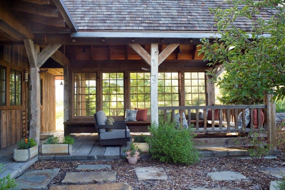 Exemple d'un porche d'entrée de maison montagne avec une terrasse en bois et une extension de toiture.