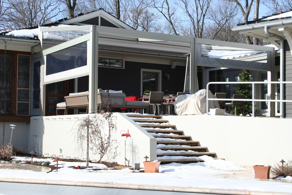 Bild på en mellanstor funkis veranda på baksidan av huset, med en öppen spis, betongplatta och markiser