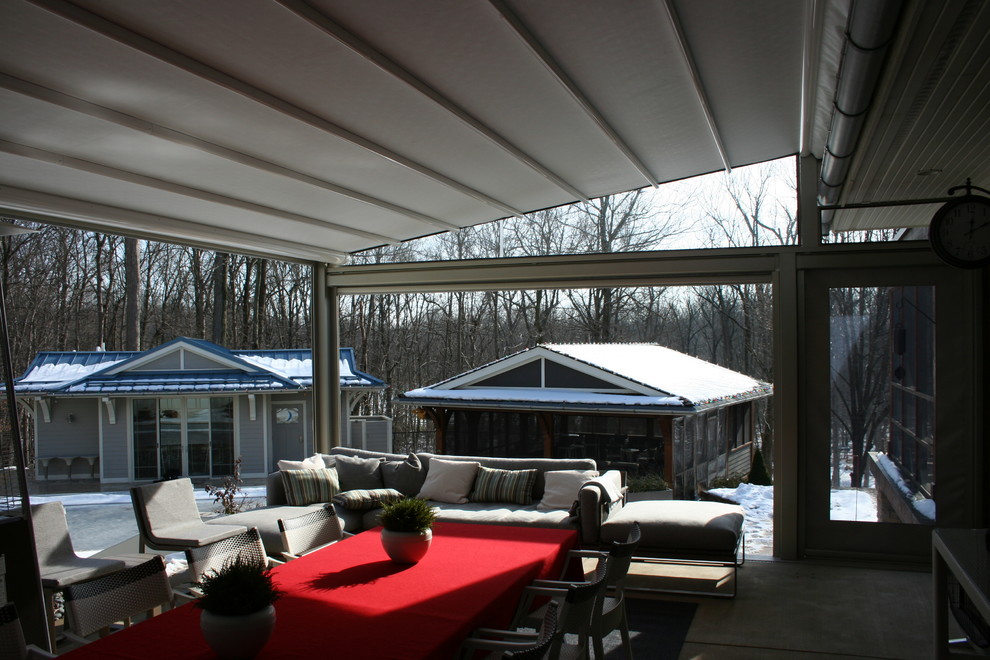 Inspiration for a mid-sized modern concrete back porch remodel in Indianapolis with a fire pit and an awning