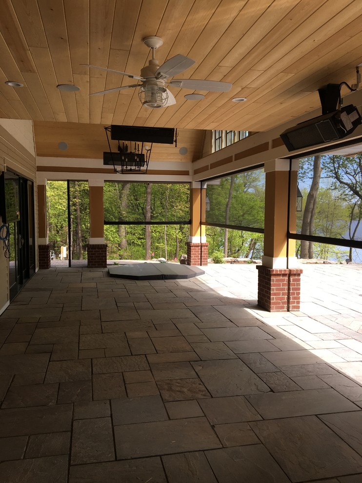 Aménagement d'un grand porche d'entrée de maison arrière classique avec des pavés en pierre naturelle et une extension de toiture.