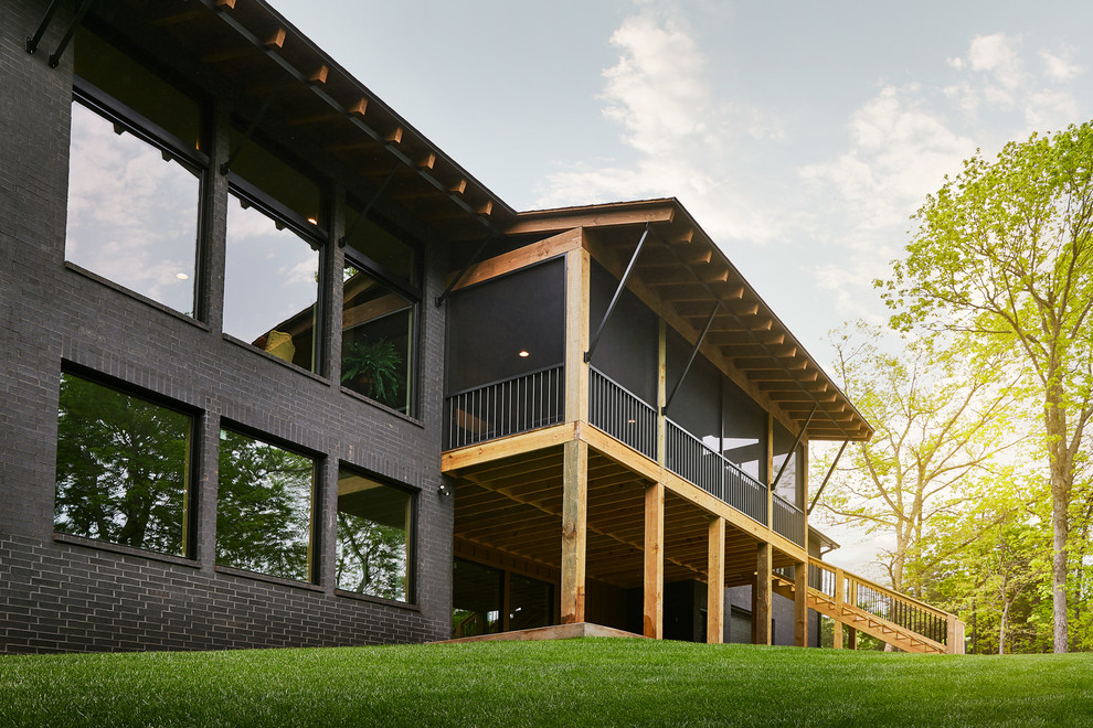 Exemple d'un grand porche d'entrée de maison arrière moderne avec une moustiquaire, une terrasse en bois et une extension de toiture.
