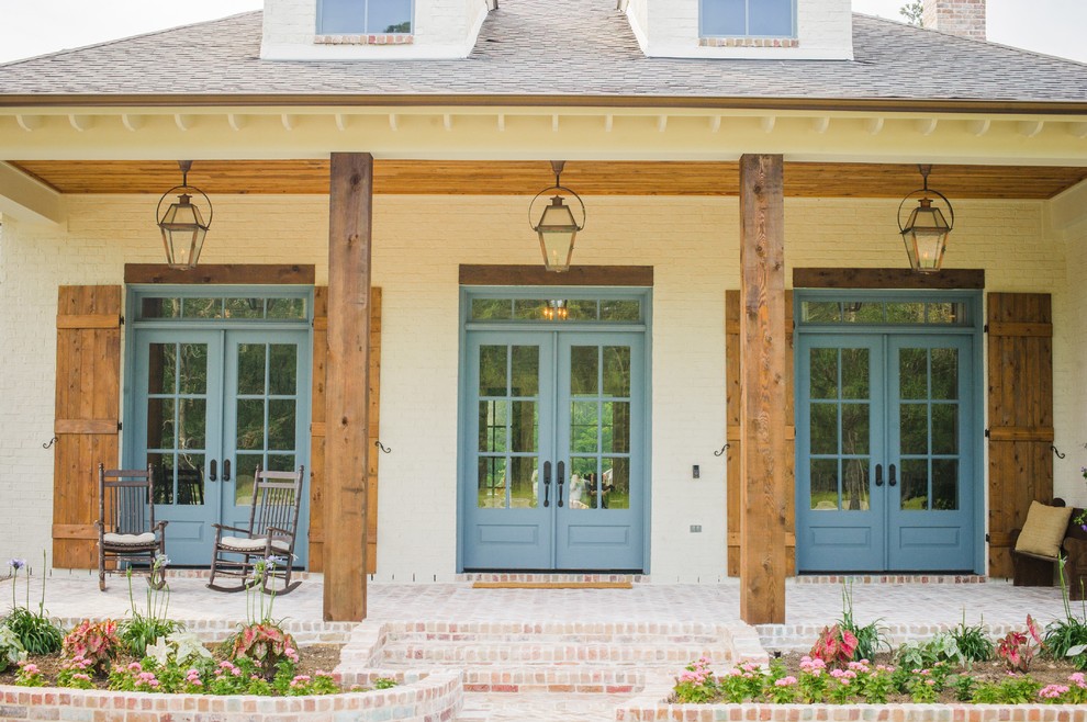 Exemple d'un grand porche d'entrée de maison avant chic avec des pavés en brique et une extension de toiture.