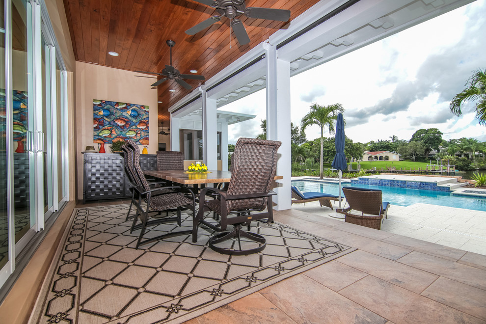 Island style tile screened-in back porch idea in Miami with a roof extension