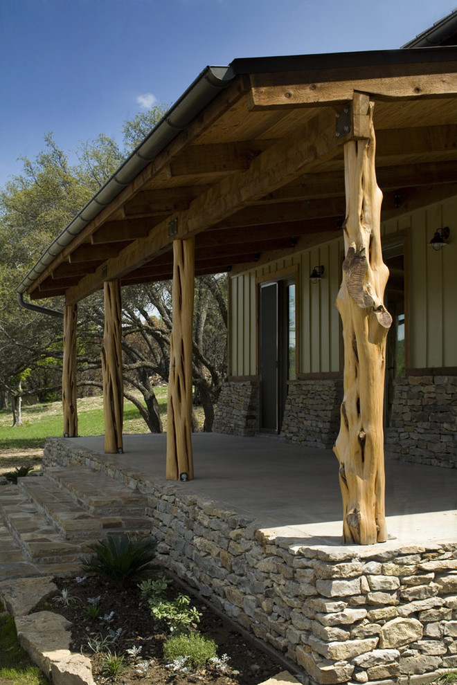 Mid-sized mountain style stamped concrete front porch photo in Austin with a roof extension
