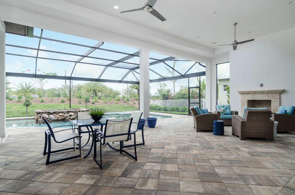 This is an example of a large contemporary stone back porch design in Miami with a fire pit and a roof extension.