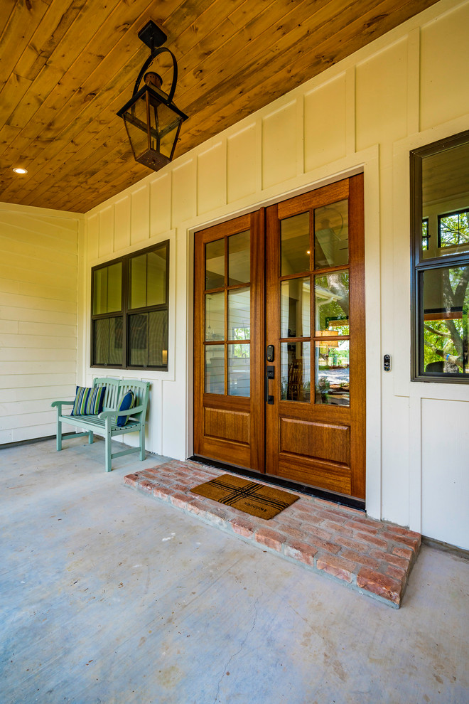 Inspiration for a mid-sized farmhouse concrete front porch remodel in Austin with a roof extension