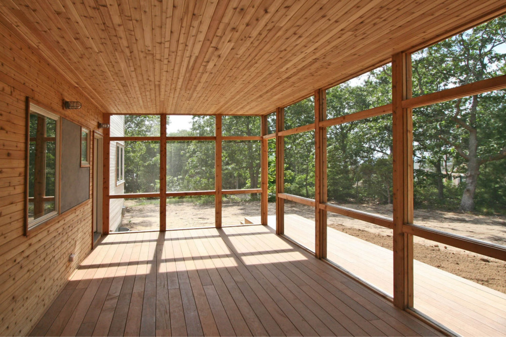 Exemple d'un porche d'entrée de maison arrière tendance de taille moyenne avec une moustiquaire, une terrasse en bois et une extension de toiture.