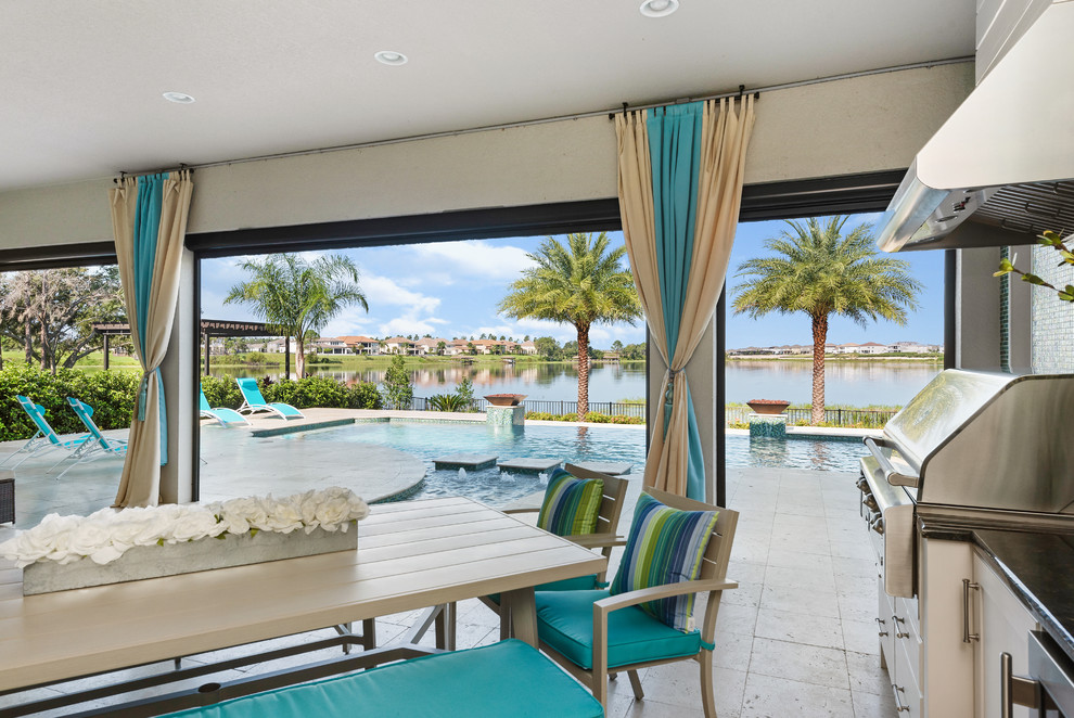 Überdachte Mediterrane Veranda hinter dem Haus mit Outdoor-Küche und Natursteinplatten in Orlando