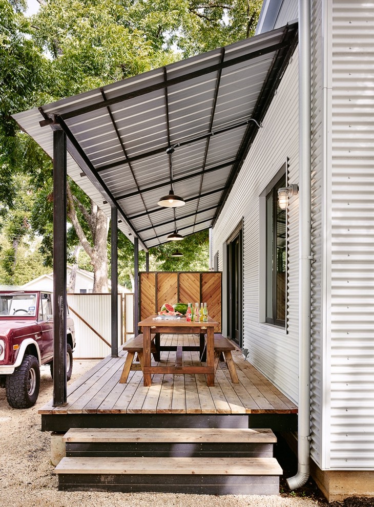 Idée de décoration pour un porche d'entrée de maison latéral champêtre avec une terrasse en bois et un auvent.