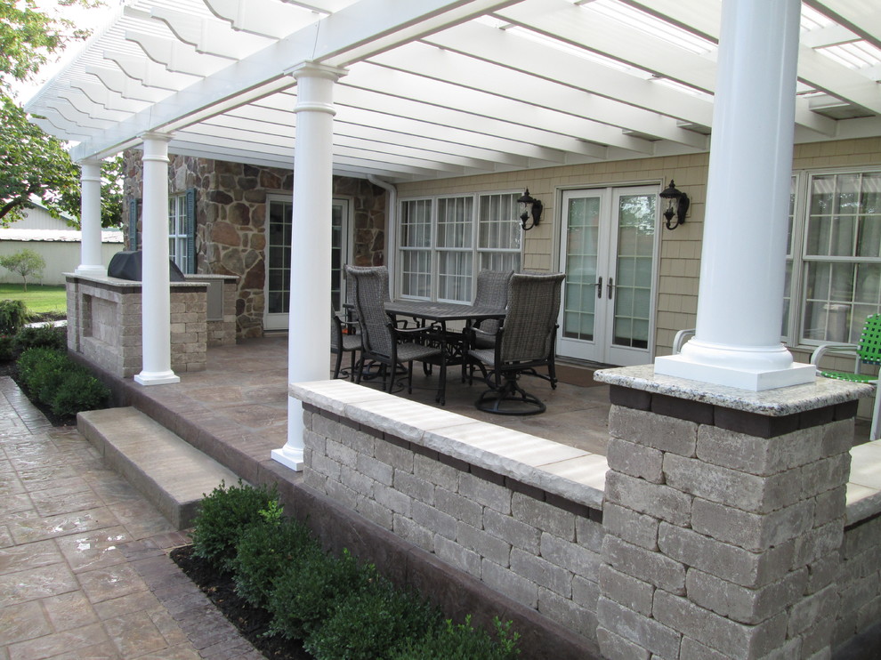 Modelo de terraza de estilo americano de tamaño medio en patio trasero con cocina exterior, adoquines de hormigón y pérgola