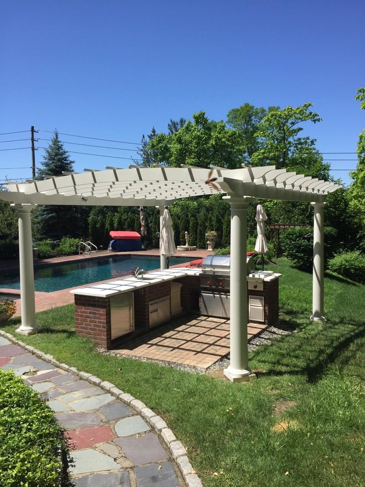 This is an example of a mid-sized transitional brick porch design in New York with a pergola.
