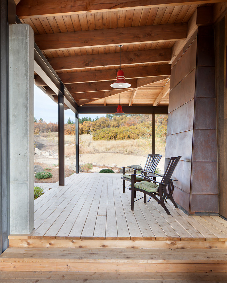 Exemple d'un très grand porche d'entrée de maison latéral tendance avec une terrasse en bois et une extension de toiture.