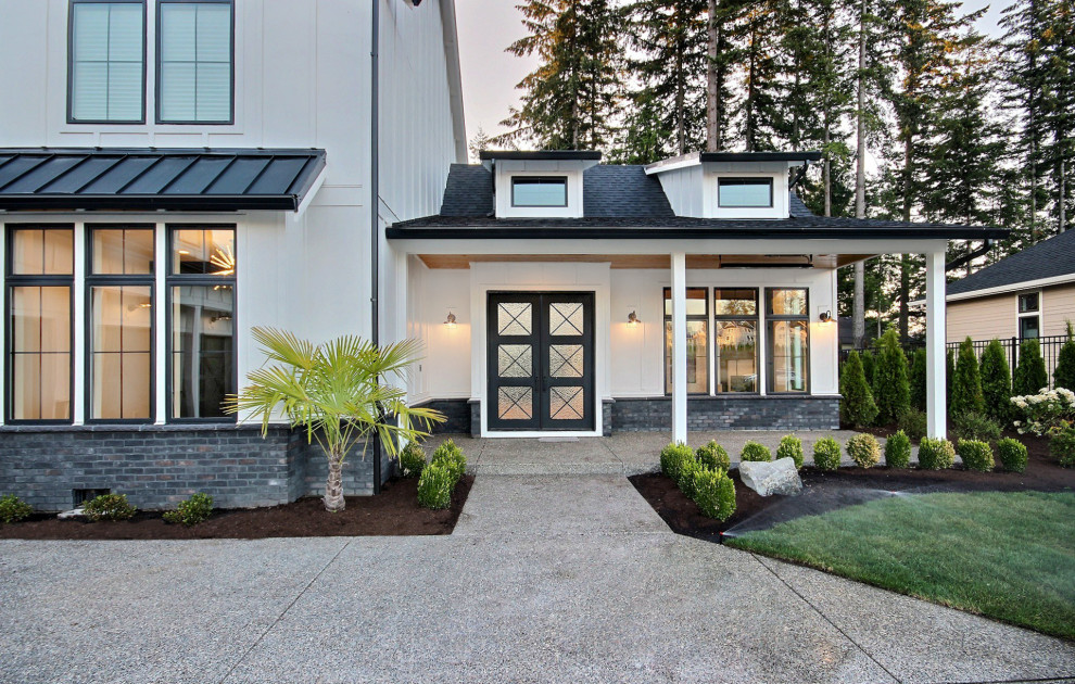 Cette photo montre un très grand porche d'entrée de maison avant nature avec une dalle de béton et une extension de toiture.