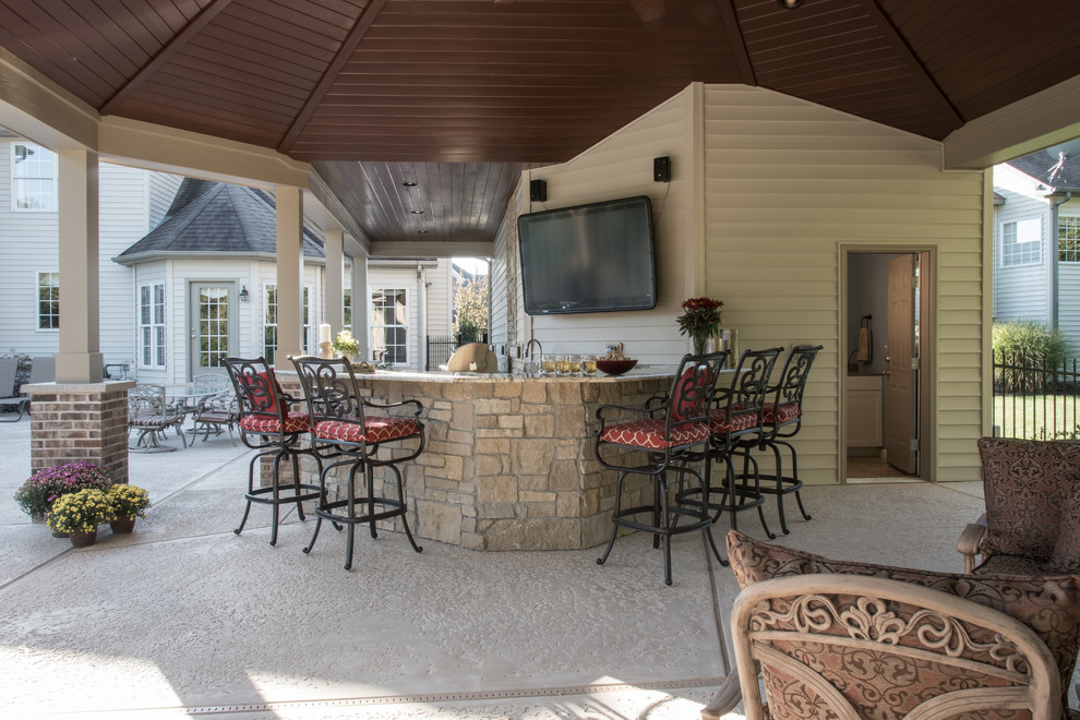 На фото: большая веранда на заднем дворе в классическом стиле с летней кухней, покрытием из декоративного бетона и навесом с