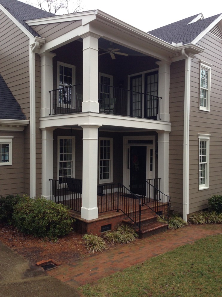 Huge elegant concrete screened-in front porch photo in Raleigh with a roof extension
