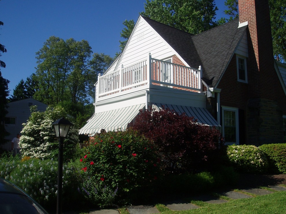 Cette photo montre un grand porche d'entrée de maison avant chic avec une moustiquaire, une dalle de béton et une extension de toiture.