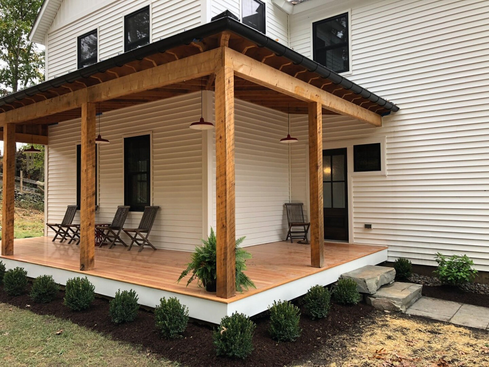 Idées déco pour un porche d'entrée de maison avant classique avec une terrasse en bois et une extension de toiture.