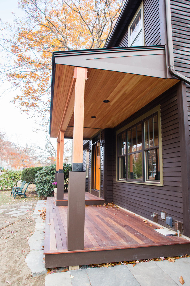 Foto på en mellanstor amerikansk veranda framför huset, med trädäck och takförlängning