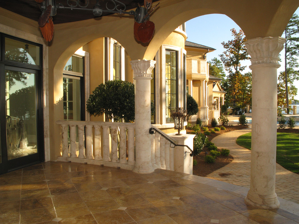 This is an example of a huge mediterranean stone side porch design in Other with a roof extension.