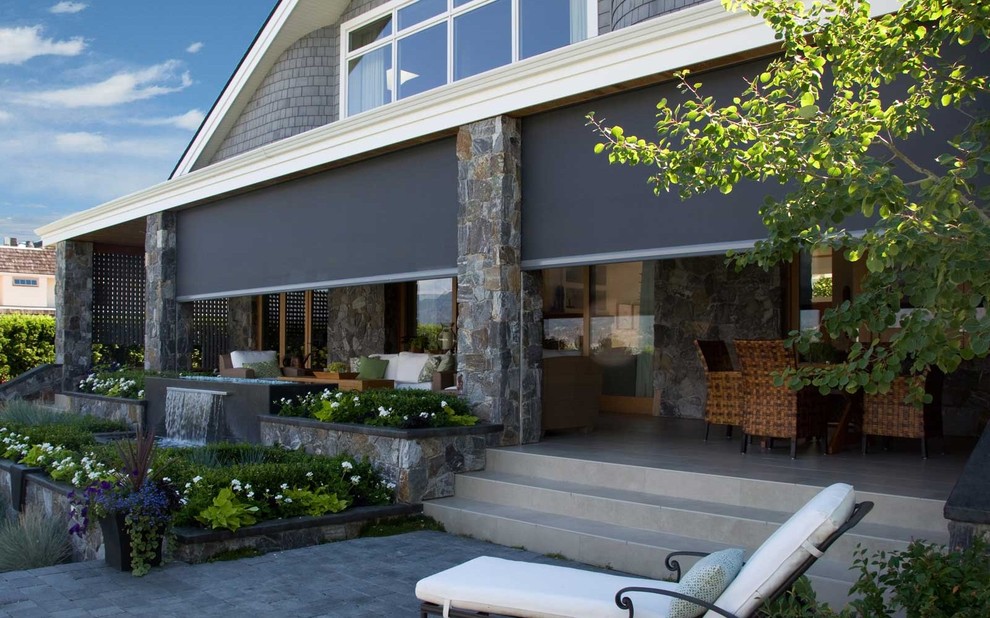 Cette image montre un grand porche d'entrée de maison arrière chalet avec des pavés en béton, une extension de toiture et une moustiquaire.