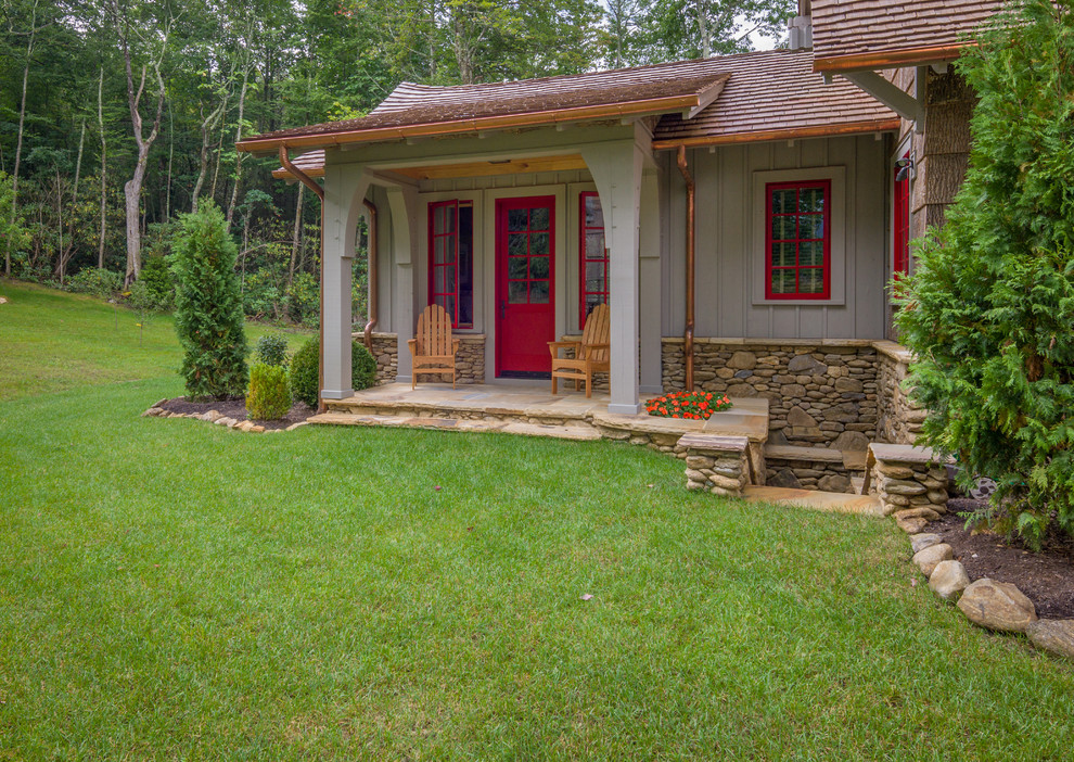 Rustik inredning av en mellanstor veranda på baksidan av huset, med naturstensplattor och takförlängning