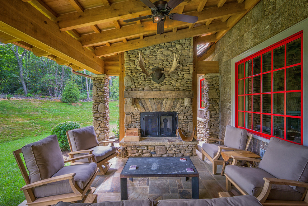 Mid-sized mountain style stone back porch photo in Charlotte with a roof extension and a fire pit