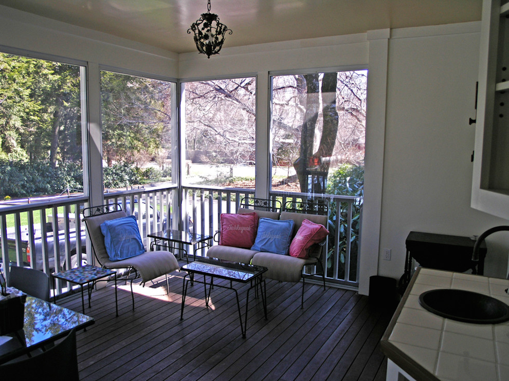 Aménagement d'un grand porche d'entrée de maison arrière classique avec une moustiquaire, une terrasse en bois et une extension de toiture.