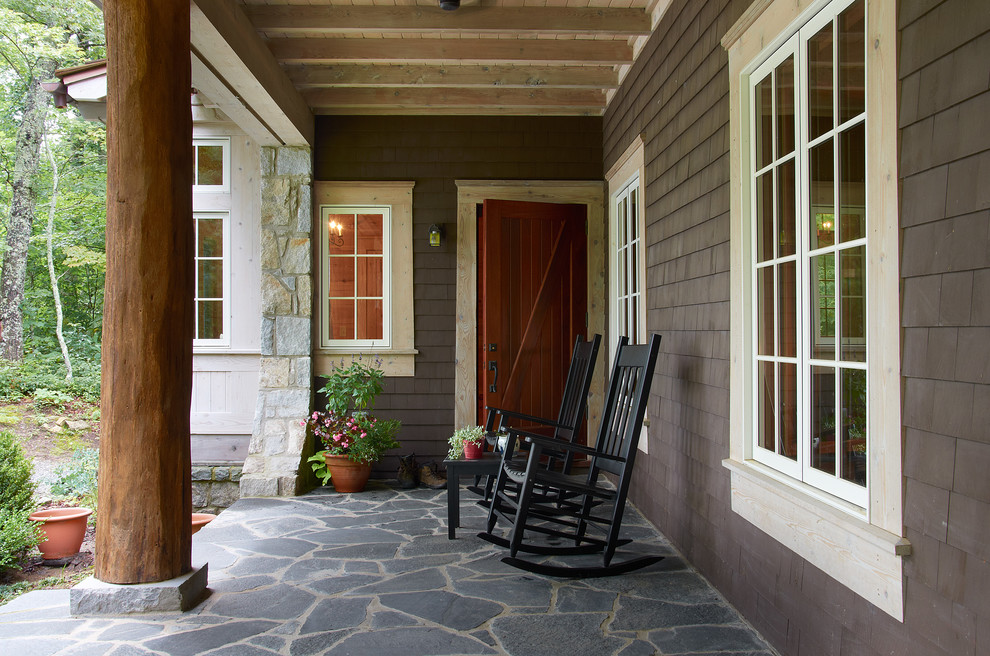 Foto di un portico country di medie dimensioni e davanti casa con pavimentazioni in pietra naturale e un tetto a sbalzo