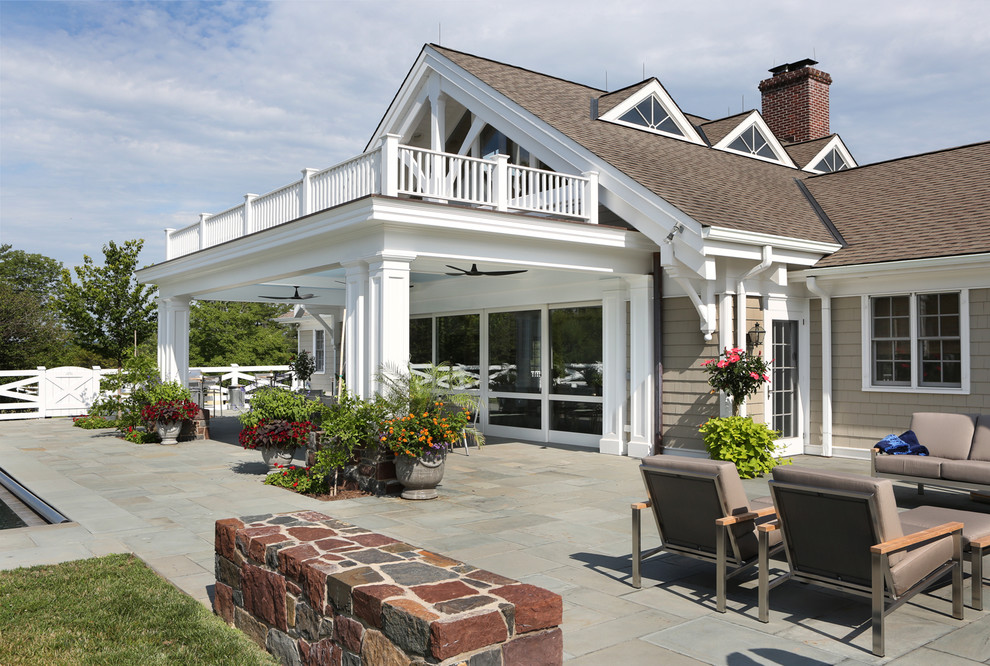 Idée de décoration pour un très grand porche d'entrée de maison arrière tradition avec des pavés en pierre naturelle et une extension de toiture.