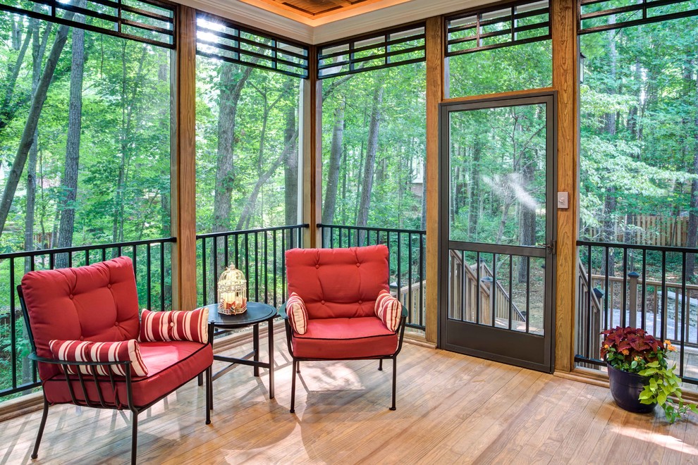 This is an example of a large craftsman screened-in back porch design in Raleigh with a roof extension.
