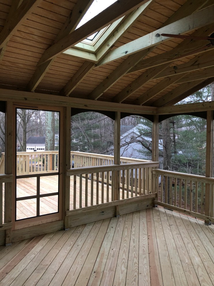 Réalisation d'un grand porche d'entrée de maison arrière tradition avec une moustiquaire, une terrasse en bois et une extension de toiture.