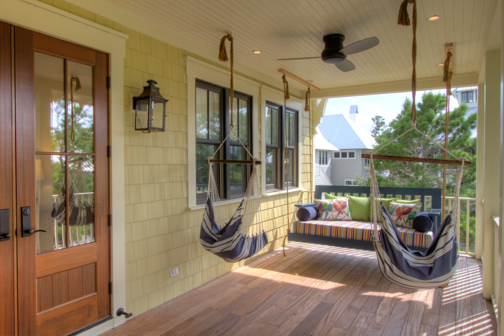 Cette photo montre un porche d'entrée de maison avant bord de mer de taille moyenne avec une terrasse en bois et une extension de toiture.