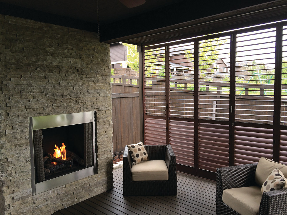 Réalisation d'un porche d'entrée de maison arrière design avec une terrasse en bois et une extension de toiture.