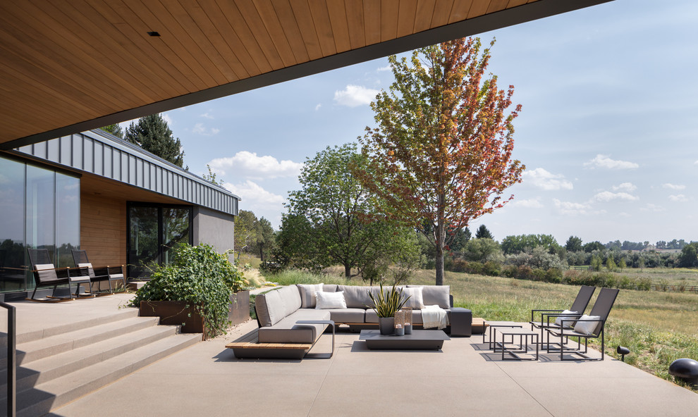 Свежая идея для дизайна: огромная веранда на заднем дворе в современном стиле с покрытием из бетонных плит - отличное фото интерьера