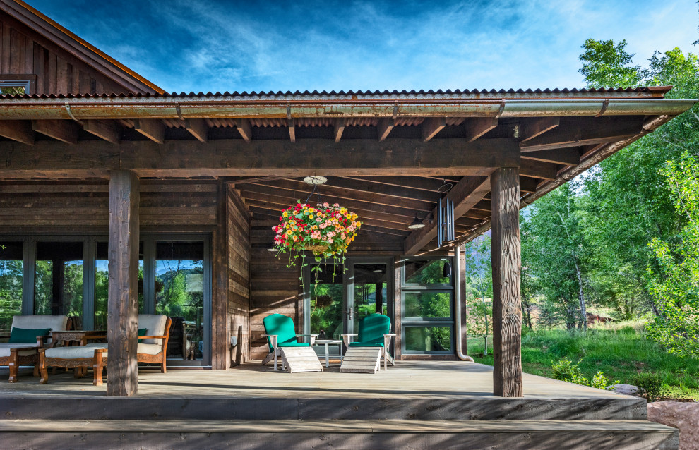 Inspiration pour un porche d'entrée de maison chalet avec une terrasse en bois et une extension de toiture.