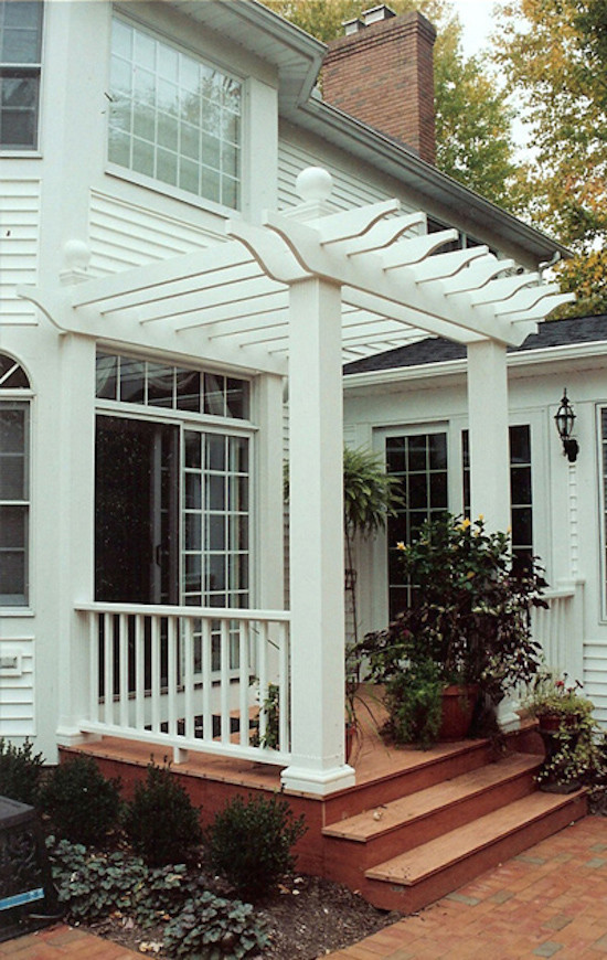 Cette image montre un porche d'entrée de maison arrière traditionnel avec des pavés en brique et une pergola.