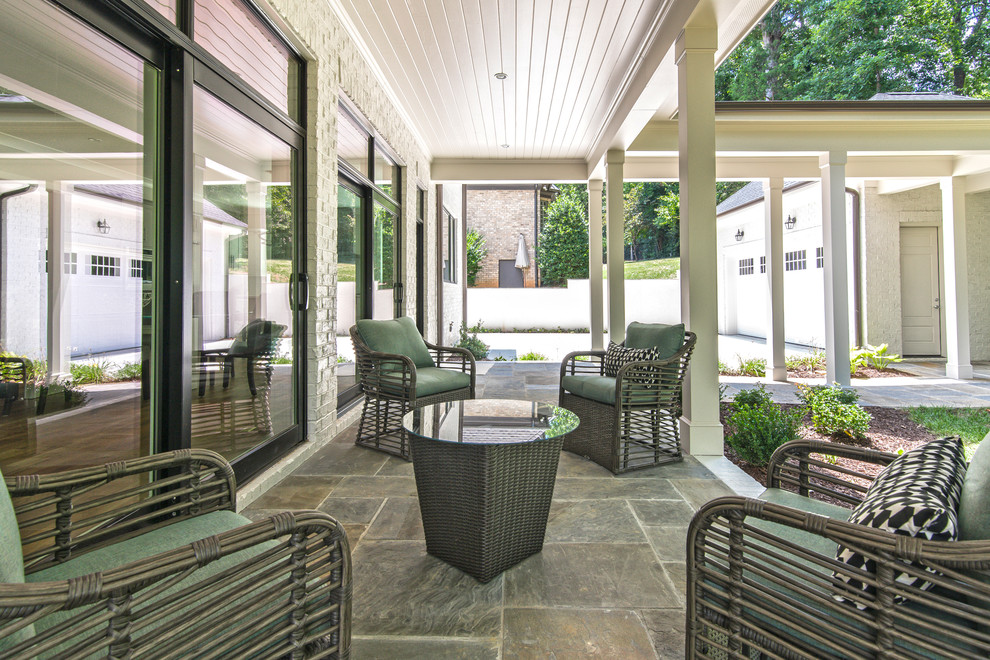 Inspiration pour un grand porche d'entrée de maison arrière traditionnel avec des pavés en pierre naturelle et une extension de toiture.