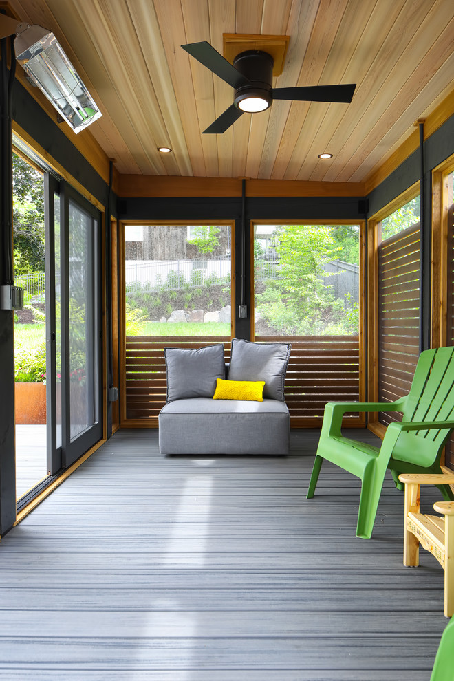This is an example of a mid-sized modern screened-in back porch design in Minneapolis with decking and a roof extension.
