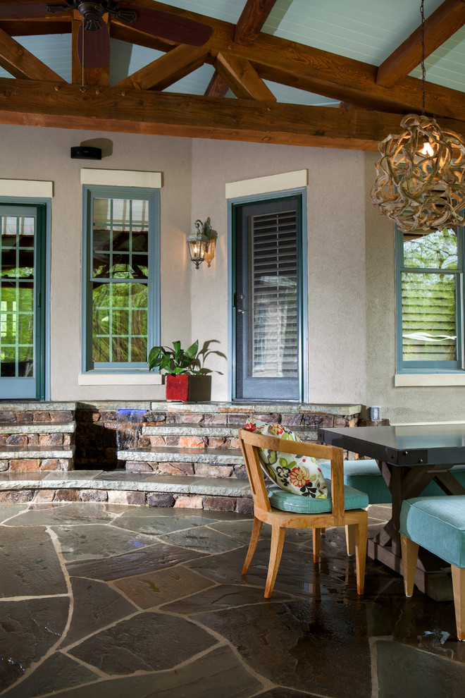 Large classic stone porch idea in Charlotte with a roof extension