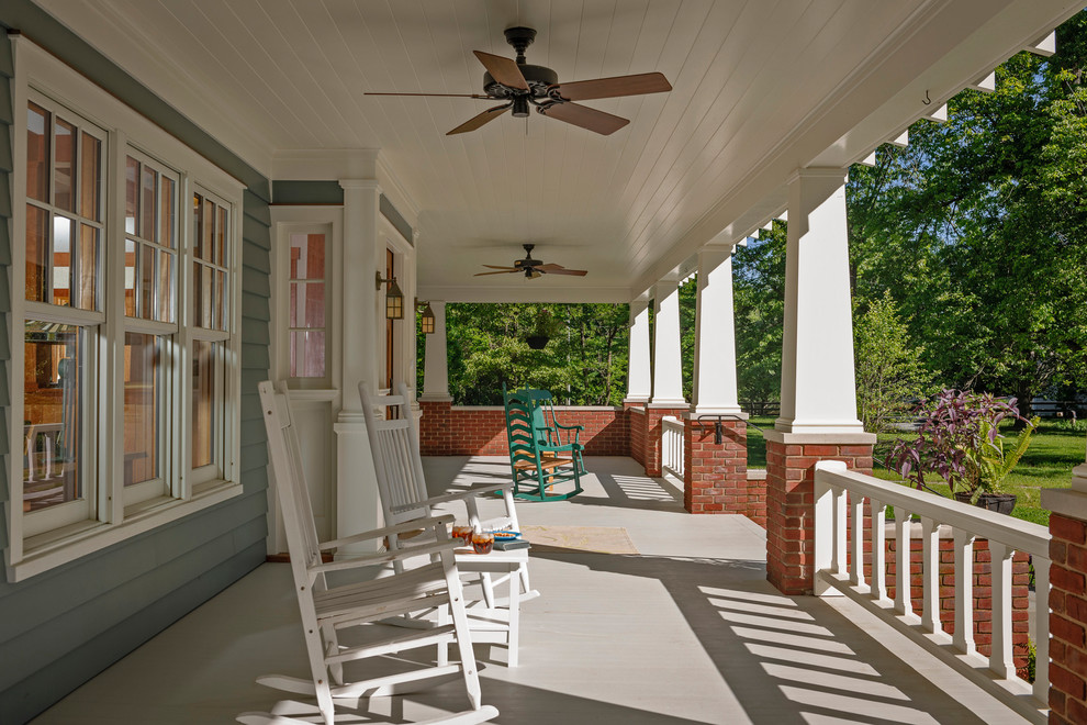 Foto på en stor amerikansk veranda framför huset, med trädäck