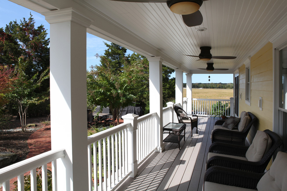Exemple d'un grand porche d'entrée de maison latéral chic avec une terrasse en bois et une extension de toiture.