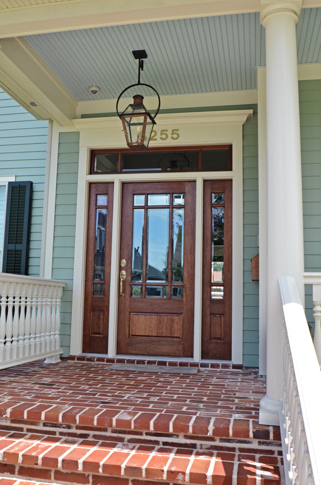 This is an example of a mid-sized craftsman brick front porch design in New Orleans with a roof extension.