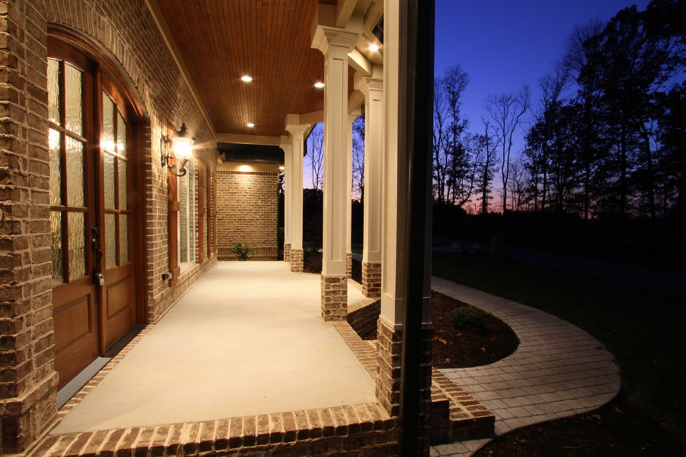 Exemple d'un porche d'entrée de maison avant chic de taille moyenne avec des pavés en brique et une extension de toiture.