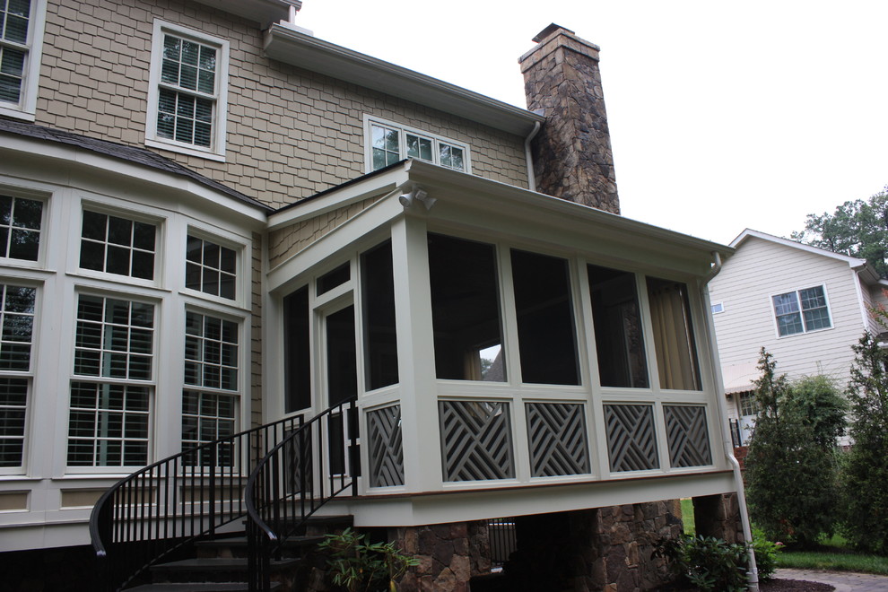 Aménagement d'un grand porche d'entrée de maison arrière classique avec un foyer extérieur, des pavés en béton et une extension de toiture.