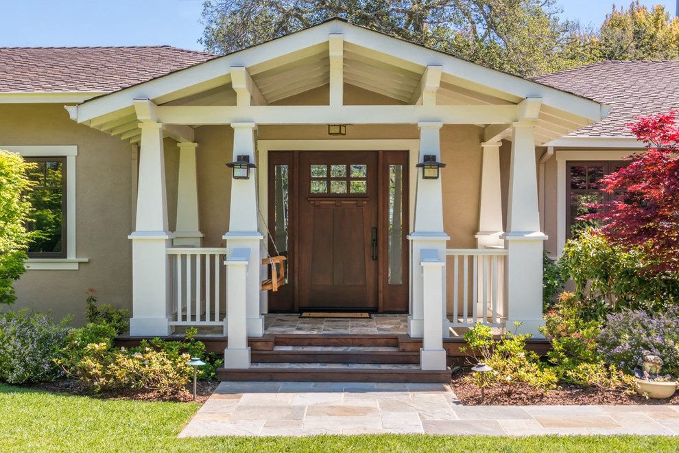 Immagine di un portico american style davanti casa con pavimentazioni in pietra naturale e un tetto a sbalzo